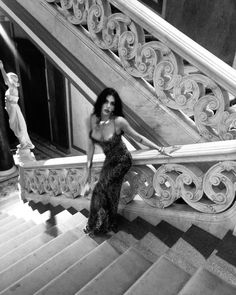 black and white photograph of a woman sitting on the stairs in front of a staircase