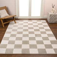 a white and gray rug with a chair in front of a window on a wooden floor