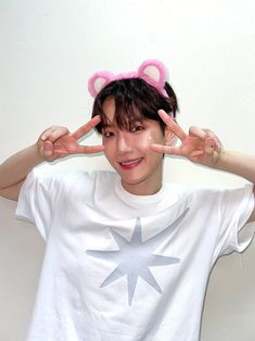 a young man wearing a white t - shirt and pink ears