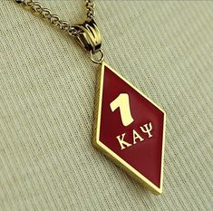 a red and gold pendant with the number one kay on it's back side