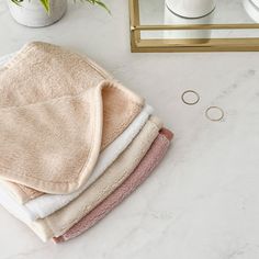 towels and rings are sitting on a marble countertop next to a mirror, vase with flowers