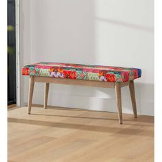 a colorful bench sitting on top of a hard wood floor next to a white wall