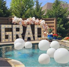 some balloons are floating in the water near a sign that says frar and is surrounded by white balls