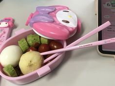 a pink bowl filled with lots of food next to a cell phone on a table