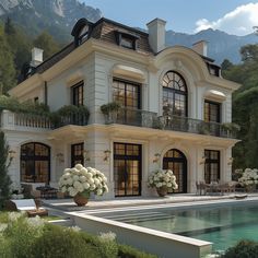 a large white house with lots of windows and flowers in front of the pool area