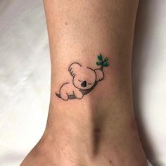 a small koala bear tattoo on the ankle with green leaves around it's neck