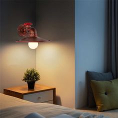 a lamp that is on in the corner of a room with a bed and pillows