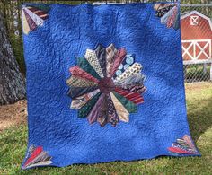 a blue quilt on the grass with a barn in the background