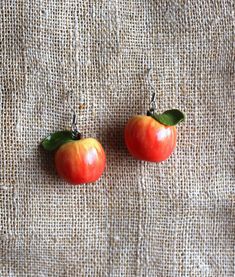 two red apples with green leaves on top of a burlly cloth background,