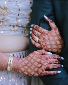 the bride and groom are holding hands with their wedding rings on them, both wearing matching bracelets