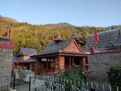 an old wooden building with a flag on the roof and mountains in the back ground