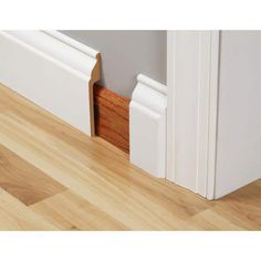 the corner of a room with wood flooring and white trim on the door frame