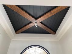 an arched window in the middle of a room with wood beams and a ceiling fan