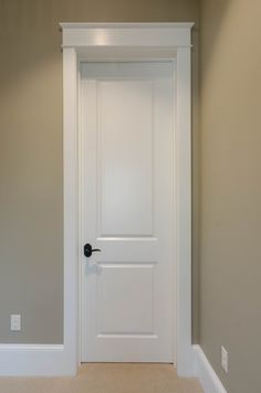 an empty room with a white door and beige carpeted flooring on the side