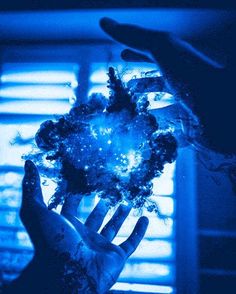 a person holding something in their hand with blue light coming from behind the window sill