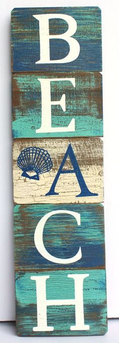 a wooden sign that says beach with shells on the bottom and blue, white and green letters