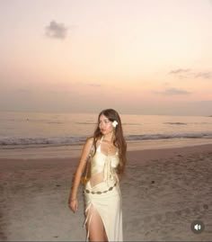 a woman standing on top of a sandy beach next to the ocean