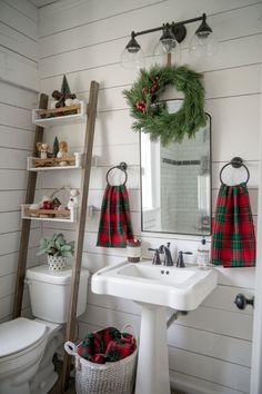 a bathroom decorated for christmas with wreaths on the window sill, toilet and sink