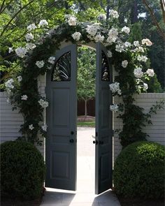 an open door to a home with white flowers on the top and bottom part of it