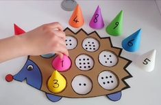 a child's hand is playing with numbers and shapes on a hedgehog craft