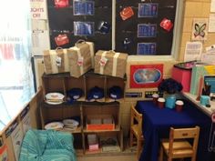 a room filled with lots of boxes and bags next to a table covered in blue cloths