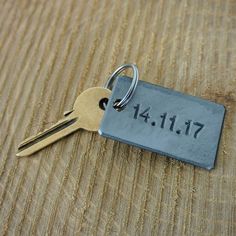 a metal keychain with a date on it sitting on top of a wooden table