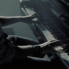 a man sitting at a piano with his hand on the keys and hands resting on the keyboard