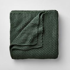 a green blanket folded on top of a white wall