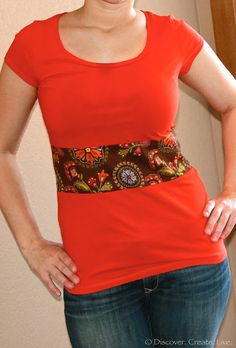 a woman standing with her hands on her hips wearing a red shirt and blue jeans