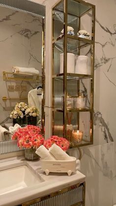 a white sink sitting under a bathroom mirror next to a shelf filled with candles and flowers