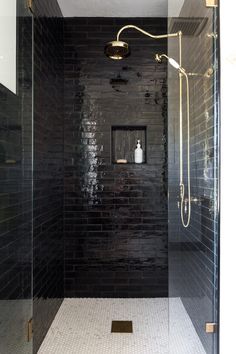 a walk in shower sitting next to a black tiled wall