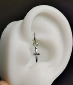 a person holding up a silver cross charm