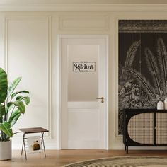 a living room with white walls and wooden flooring next to a potted plant