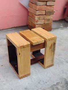 two wooden tables sitting next to each other on the ground near a brick wall and pink building