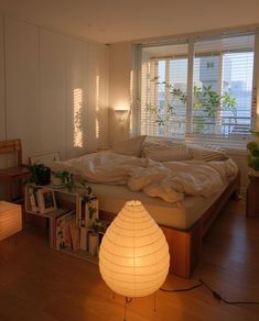 a bedroom with a bed, lamp and bookshelf in it's corner