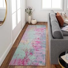 a living room with a gray couch and pink rug