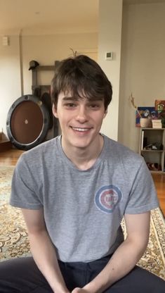 a young man sitting on top of a rug