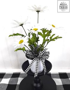 a vase filled with white flowers on top of a black table next to a wall