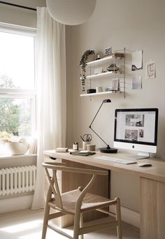 a desk with a computer on top of it next to a window and a chair