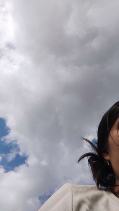 a woman is flying a kite in the air with clouds behind her and blue sky