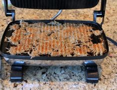 a grill with food cooking in it on top of a counter next to a plate