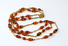 1950s Tiger stripes Honey Topaz  Glass in gold tone metal necklace .  BEAUTIFUL.Rare .  BEAUTIFUL elegant  necklace is perfect for any time of the day or night out . Just gorgeous. It is as fashionable today as is was years ago!!  This necklace is in a good vintage condition , The length is 59cm  .  A truly beautiful piece of vintage jewellery. As this is a pre-owned vintage item, please take a close look at the photos as they are part of the description.  If you are unhappy with your purchase, please contact us so I can resolve things for you :) NOTES TO OVERSEAS CLIENTS: International customers are responsible for all fees imposed, including import taxes, customs duties, and fees levied by the buyer's country. These charges are not included in the item price or the shipping charge and wi Vintage Yellow Gold Double Strand Necklaces, Mid-century Gold Necklace Gift, Vintage Gold Double Strand Necklace, Vintage Glass Necklaces For Formal Occasions, Metal Necklace, Elegant Necklace, Tiger Stripes, Elegant Necklaces, Metal Necklaces