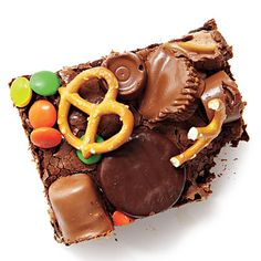 a piece of chocolate cake topped with candy and pretzels