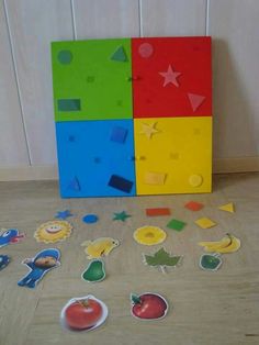 several pieces of cut out paper sit on the floor next to each other in front of a colorful box