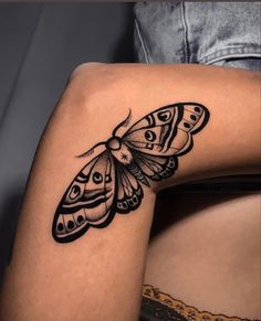 a woman's thigh with a black and white butterfly tattoo on the side of her leg