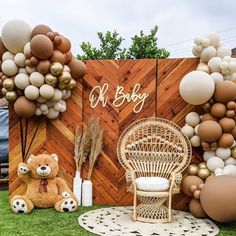 a teddy bear sitting on top of a grass covered field next to a wooden fence