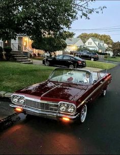 an old car is parked on the side of the road in front of some houses