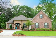 a brick house with green grass and trees in the background