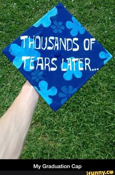 a blue graduation cap that says thousands of tears later on the grass with paw prints