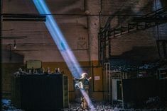 a person standing in an industrial area with a light beam